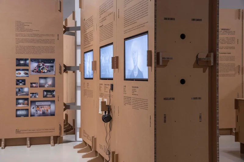 Close view of cardboard panels with embedded screens displaying video content and mounted shelf brackets