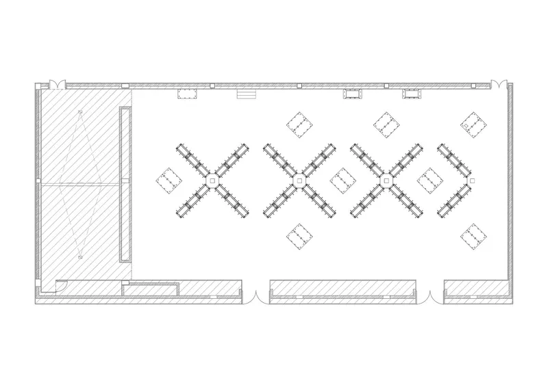 Floor plan drawing showing a rectangular room with four X-shaped desk clusters and adjacent service space