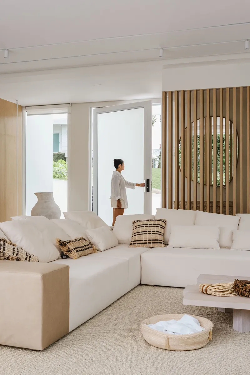 Living room with vertical timber screen and a figure opening glazed doors to the garden