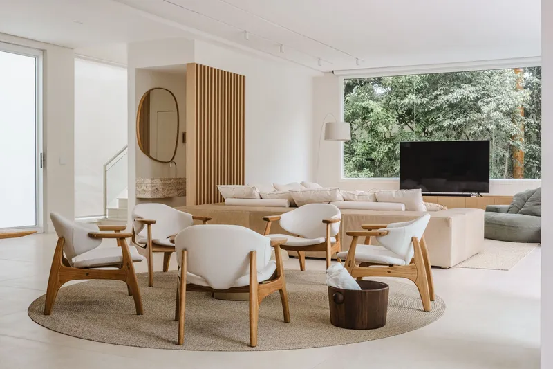 Open living area with timber-slatted screen dividing dining and lounge zones under track lighting