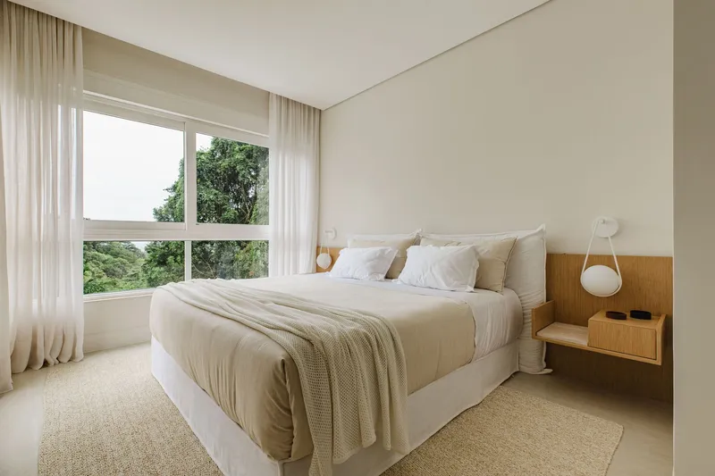 Bedroom with timber headboard panel and horizontal window framing views of surrounding vegetation