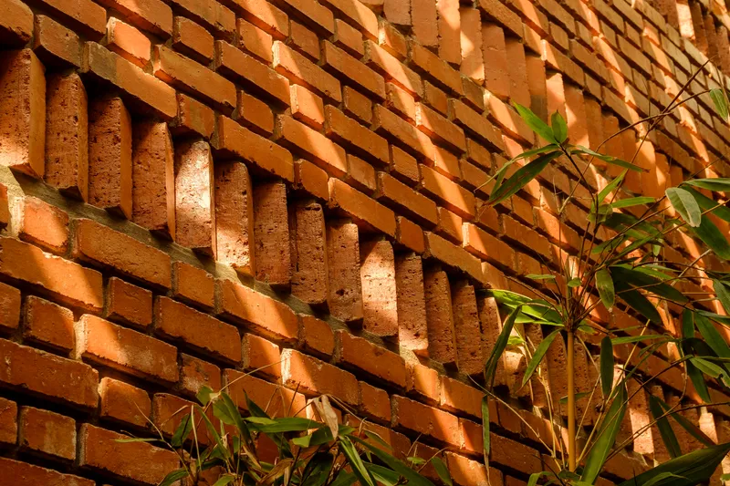 Close-up of projecting brick coursing creating a textured wall pattern with bamboo leaves casting shadows in sunlight
