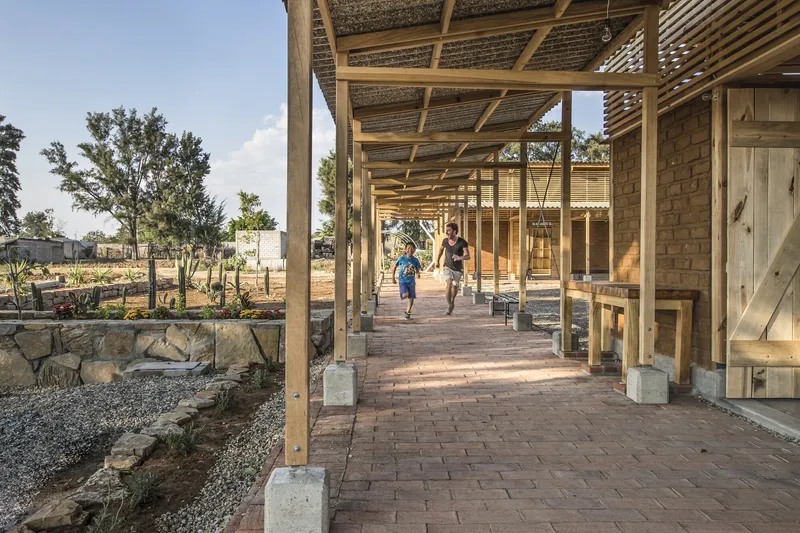 Covered walkway with exposed timber framing and brick pavers as two children run through