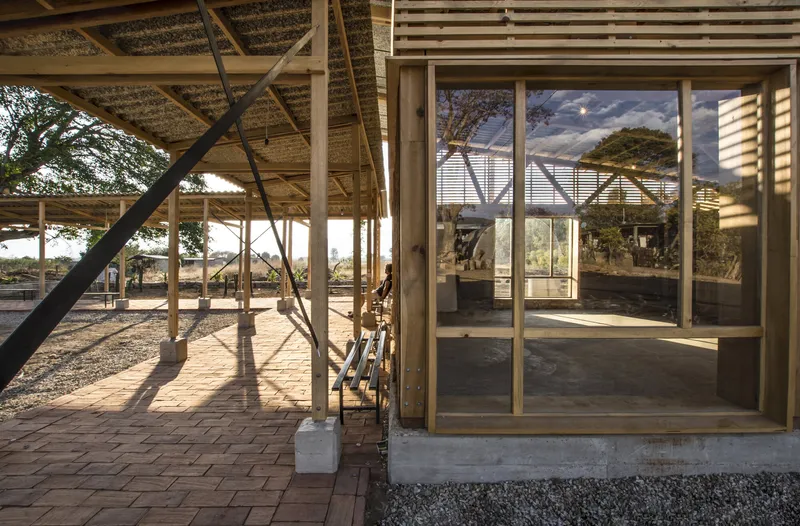 Glass door threshold connecting interior space to covered terrace with steel diagonal bracing at dusk