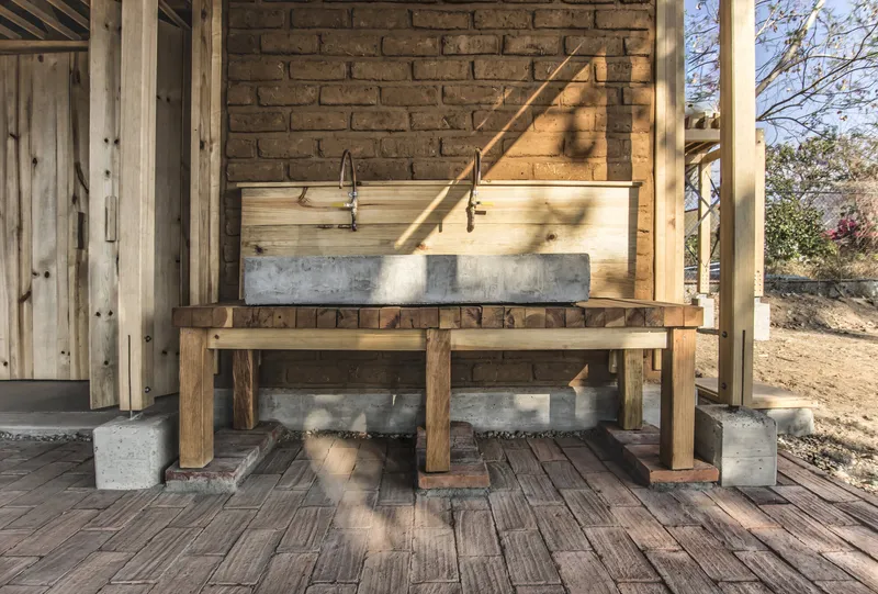 Outdoor sink with concrete basin and timber frame structure on brick paver flooring