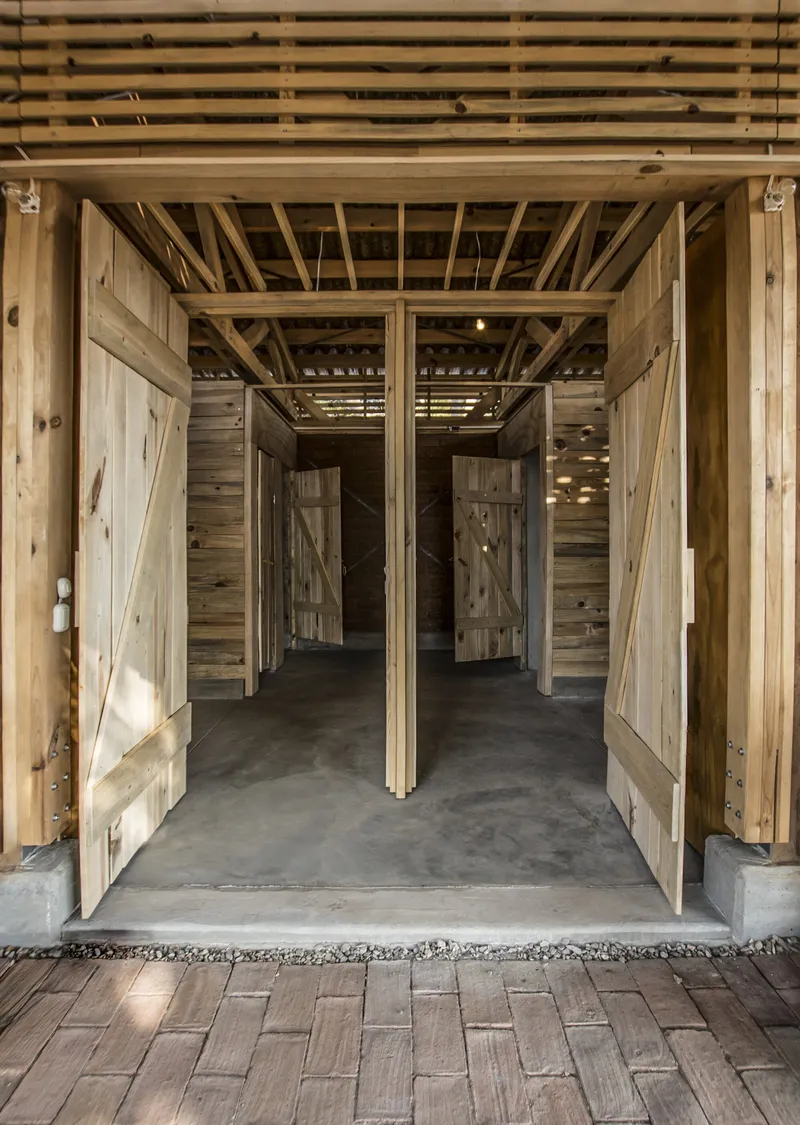 Interior view through open timber barn doors revealing exposed wood framing and concrete floor