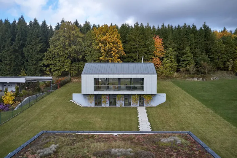 Aerial view showing the split-level section with upper metal volume and lower white concrete base
