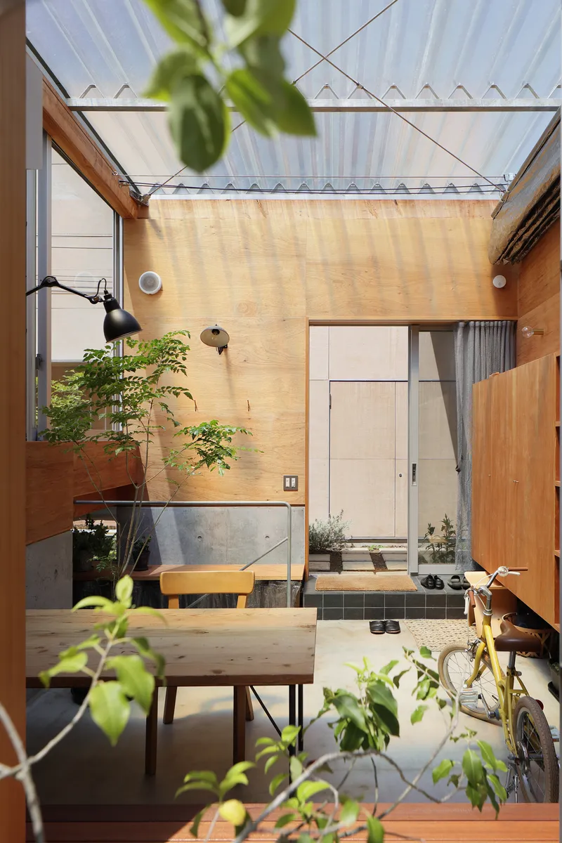 Interior courtyard with plywood walls, corrugated skylight and potted plants framing the view