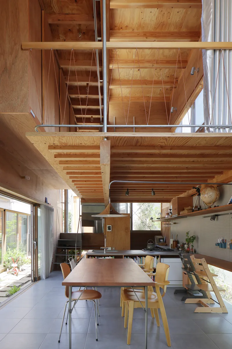 Double-height dining space beneath an exposed timber mezzanine and open stair structure