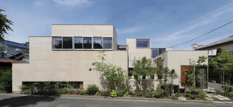 Street elevation with pale facade panels, ribbon windows and landscaped frontage under a clear sky