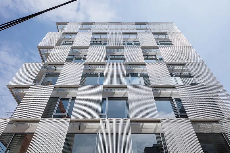 Looking up at the gridded facade showing vertical ribbed panels alternating with recessed window openings and balconies