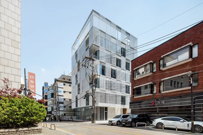 White paneled facade with vertical ribs and recessed windows under a clear sky