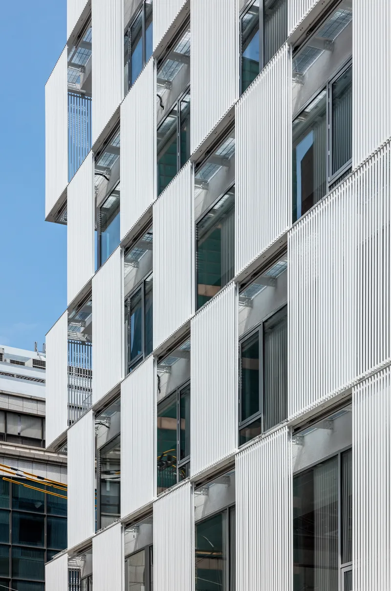 Diagonal view of the ribbed white cladding framing recessed balconies and glazed openings