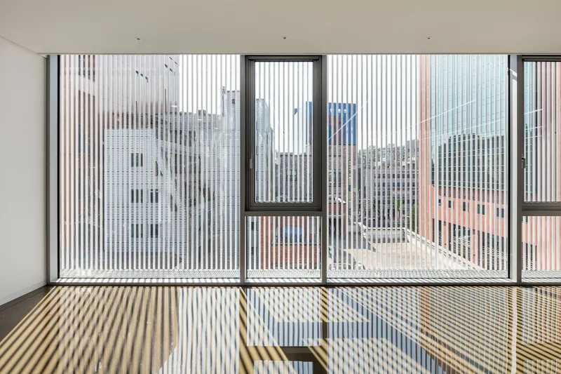 Interior view through vertical screen louvres casting striped shadows on the floor and balcony