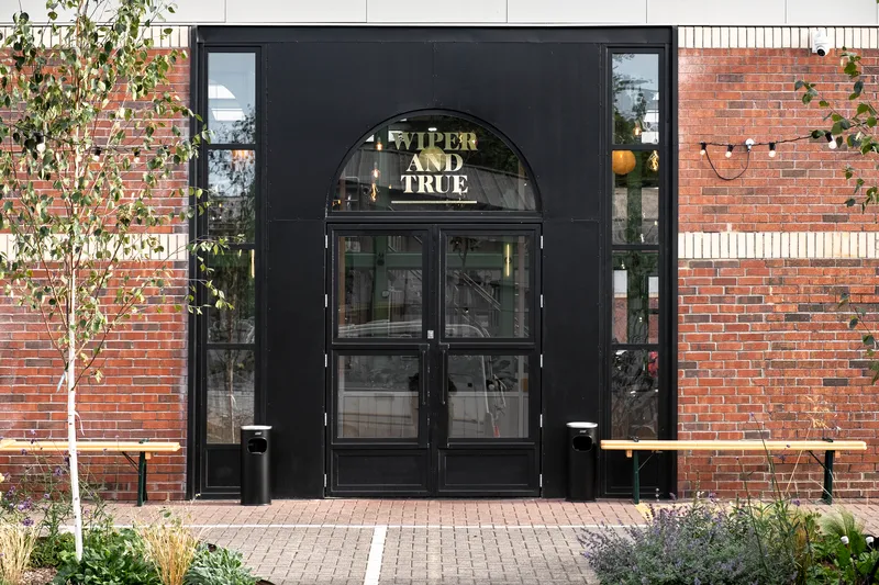 Black metal entrance doors with arched transom set within a dark frame against red brick walls
