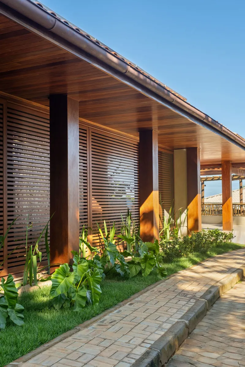 Horizontal wood slat screens between timber columns with planted bed catching afternoon light