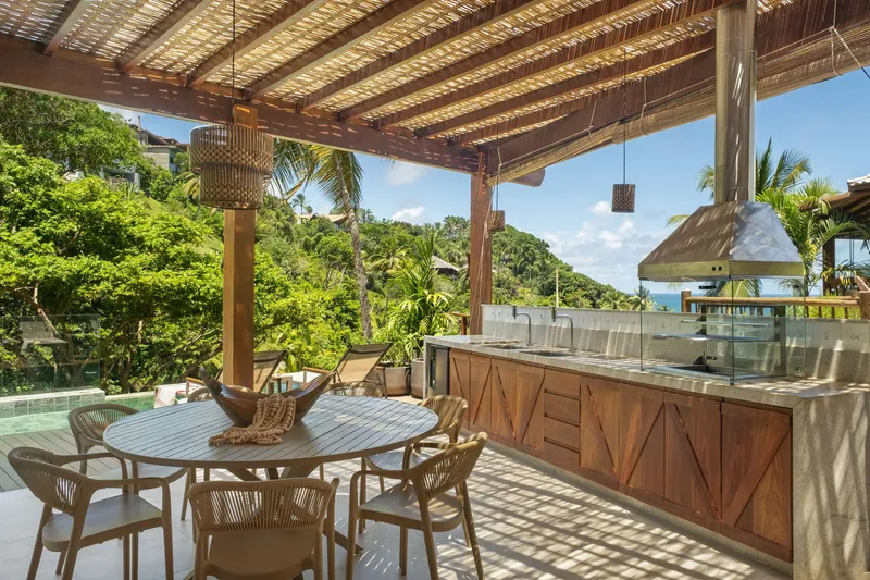 Covered outdoor dining terrace with woven bamboo roof and views to hillside vegetation