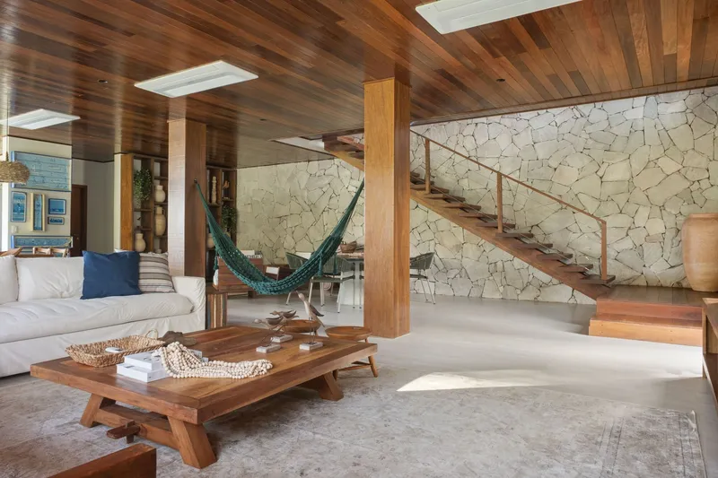 Floating timber staircase with steel railing ascending against a cream stone mosaic wall
