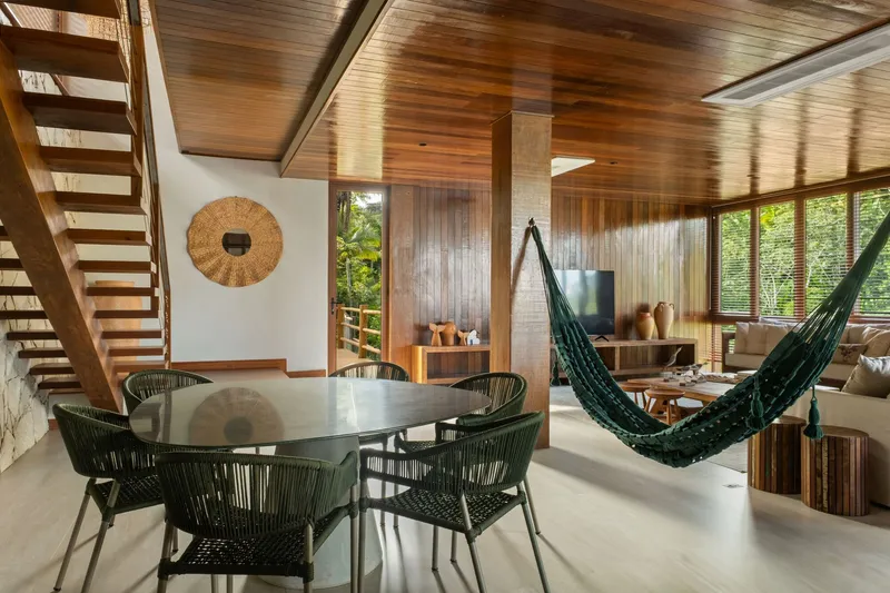 Double-height living area with timber staircase, clerestory windows and a hammock suspended between columns