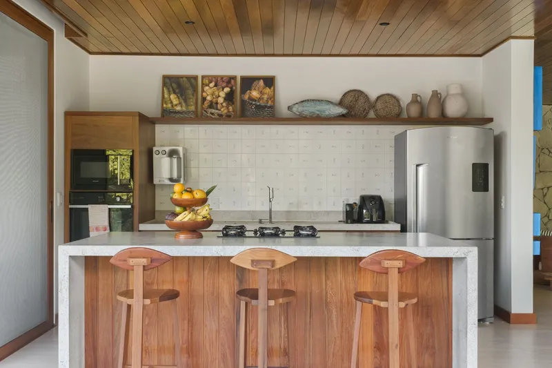 Kitchen counter with white tile backsplash and three timber bar stools beneath a wood plank ceiling