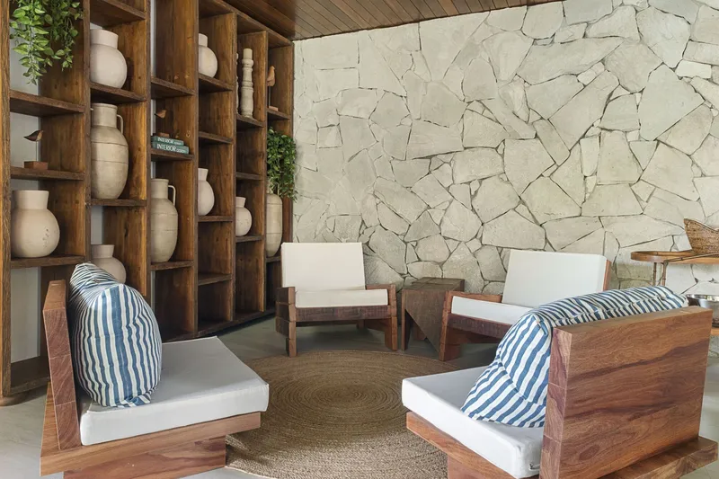 Seating nook with timber lounge chairs, striped cushions and a stone mosaic accent wall