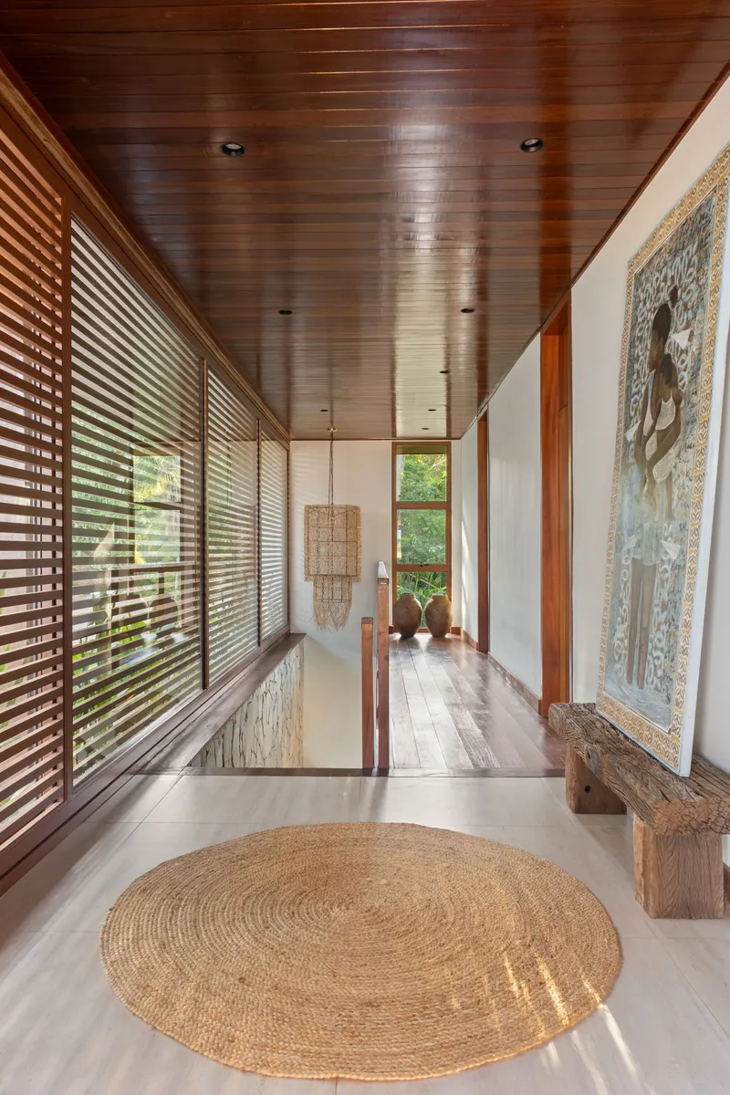 Corridor with timber ceiling and horizontal louvered screens overlooking greenery
