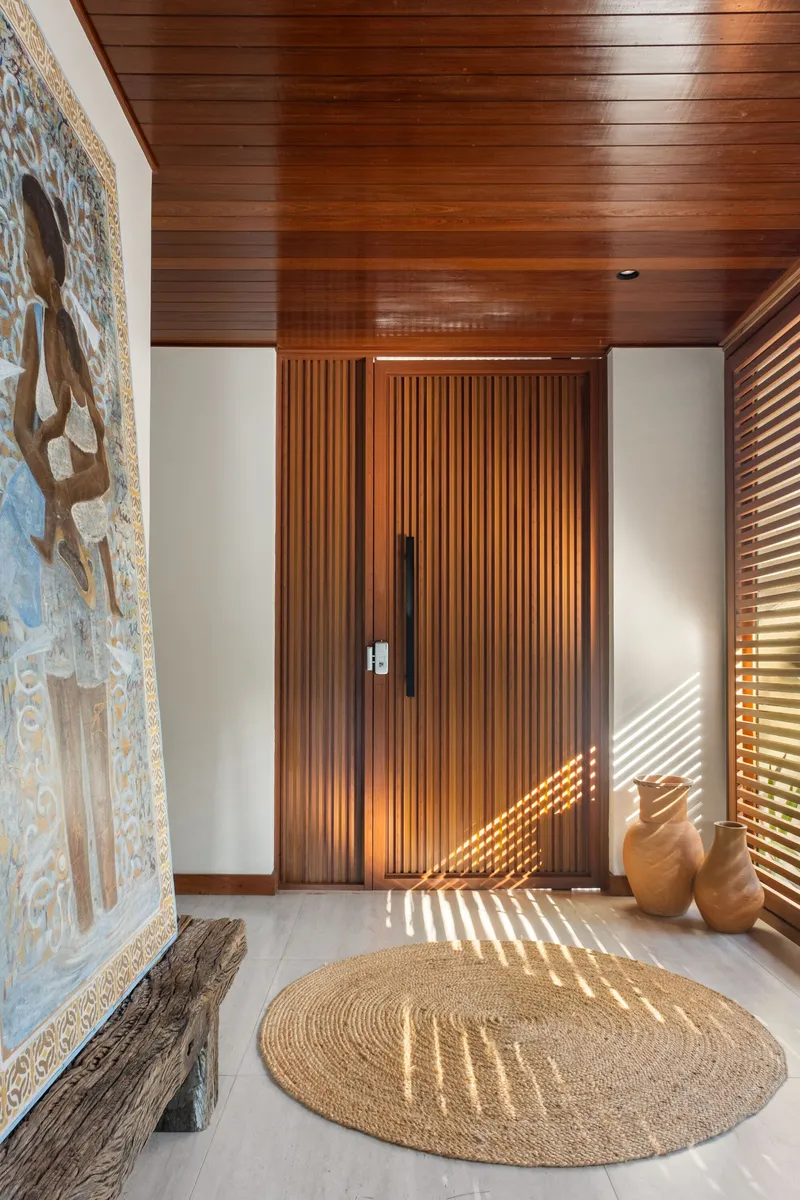 Entry vestibule with vertical slat timber door and striped shadows from adjacent louvers