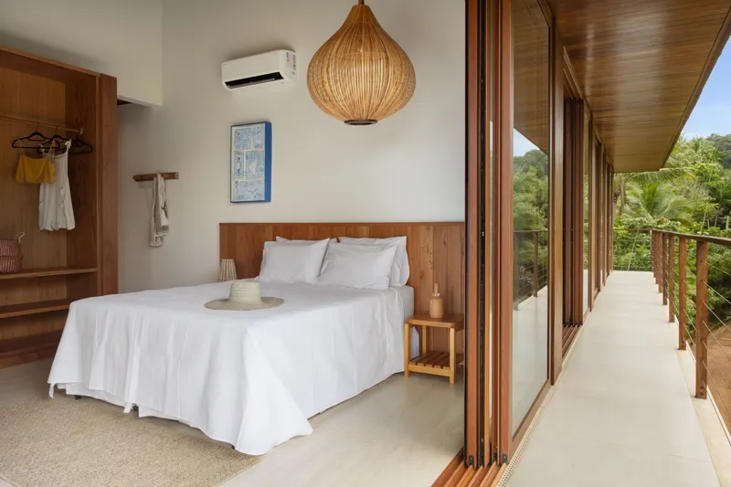 Bedroom opening to an exterior timber balcony with views of palm trees