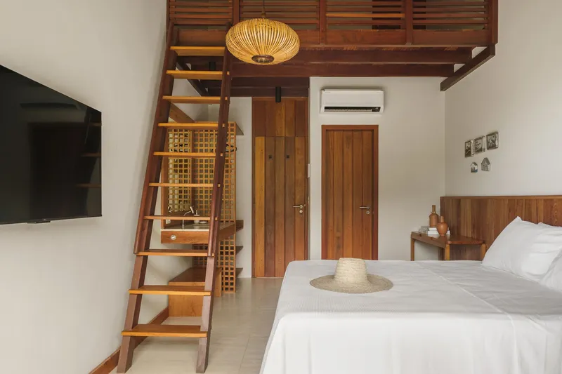 Bedroom with timber ladder accessing a mezzanine storage loft above