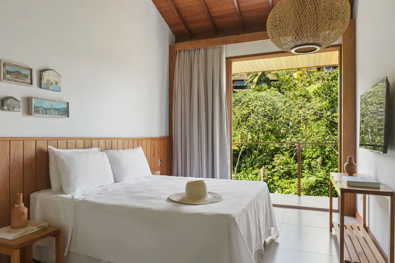 Interior view with exposed timber ceiling beams and corner glazing overlooking hillside greenery