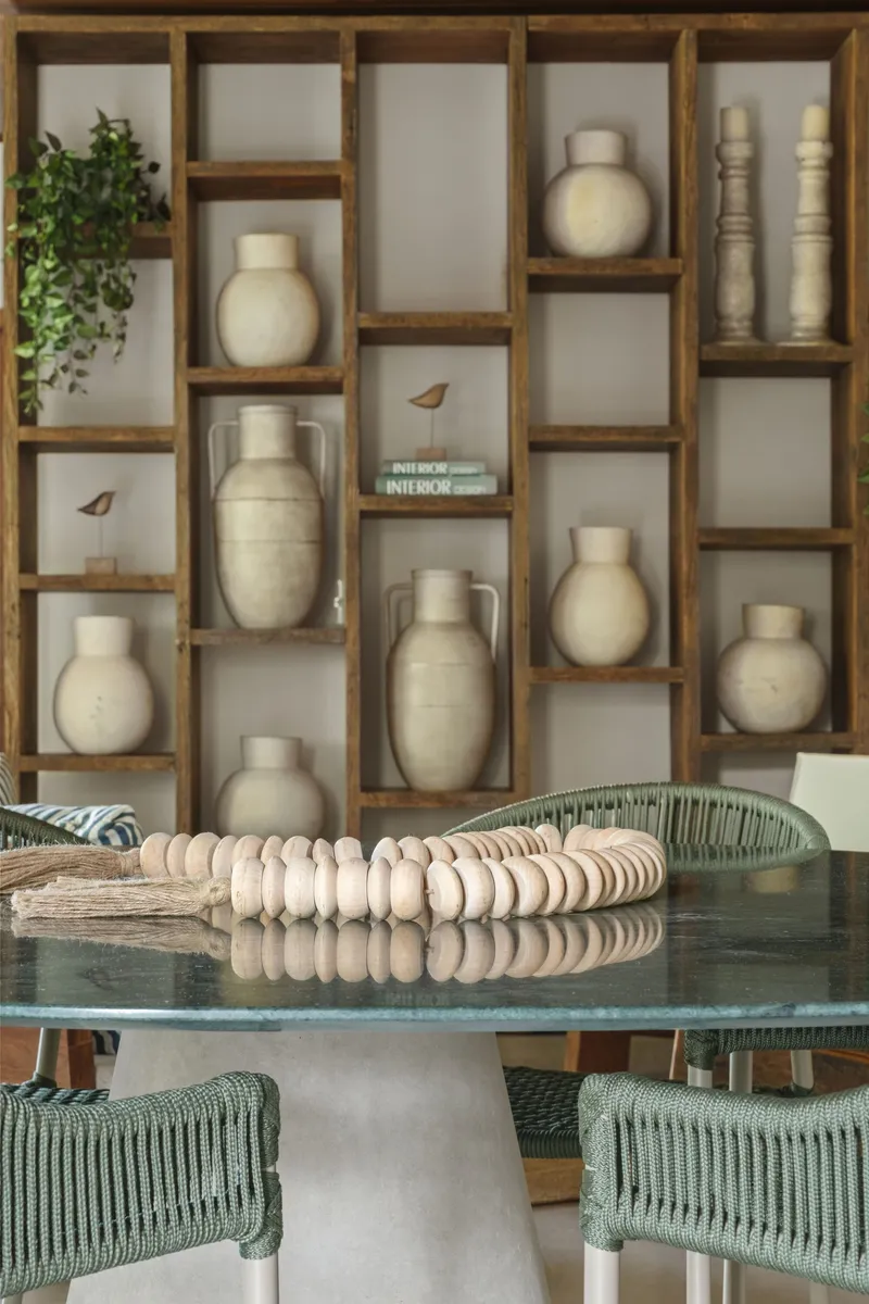 Timber grid shelving unit with ceramic vessels above round dining table