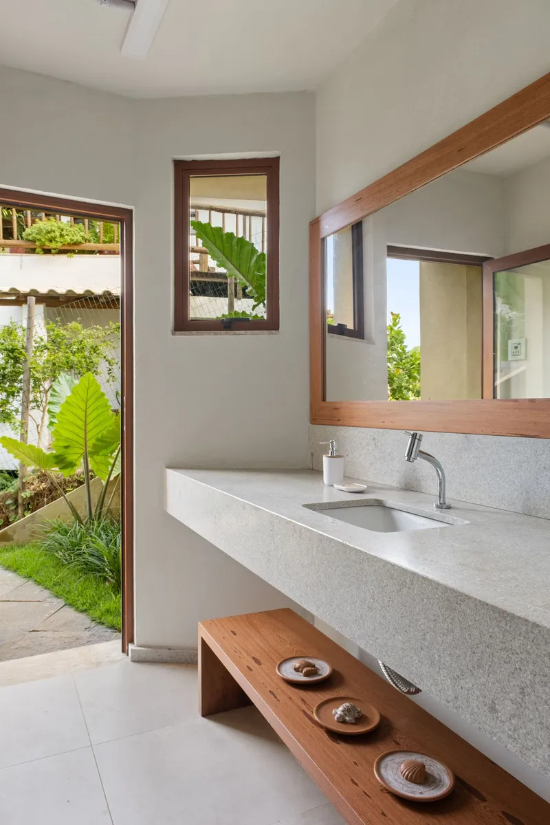 Bathroom with terrazzo vanity and timber-framed mirrors opening to a planted courtyard with tropical foliage