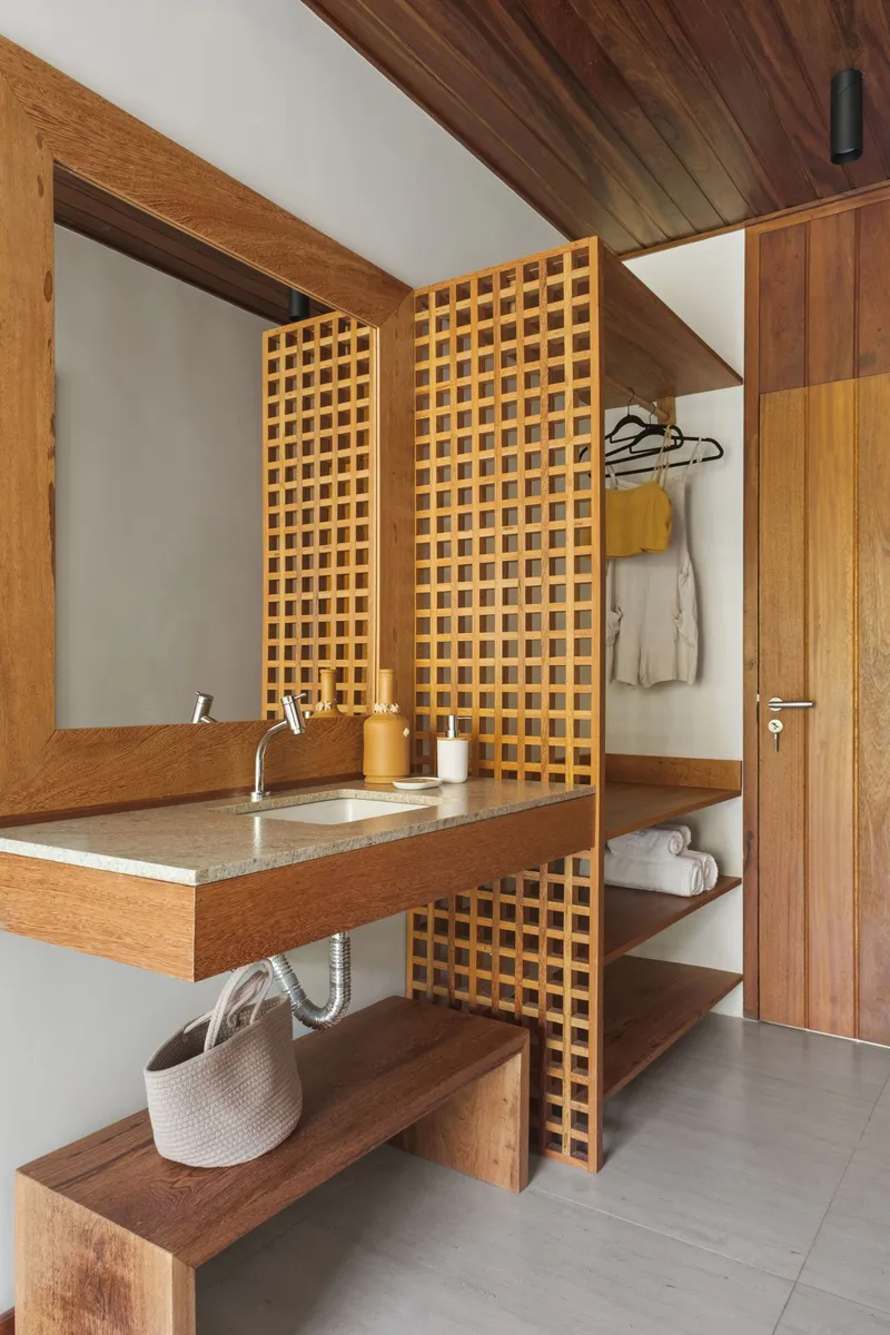 Bathroom vanity flanked by lattice timber screens with integrated shelving and a sloped ceiling panel