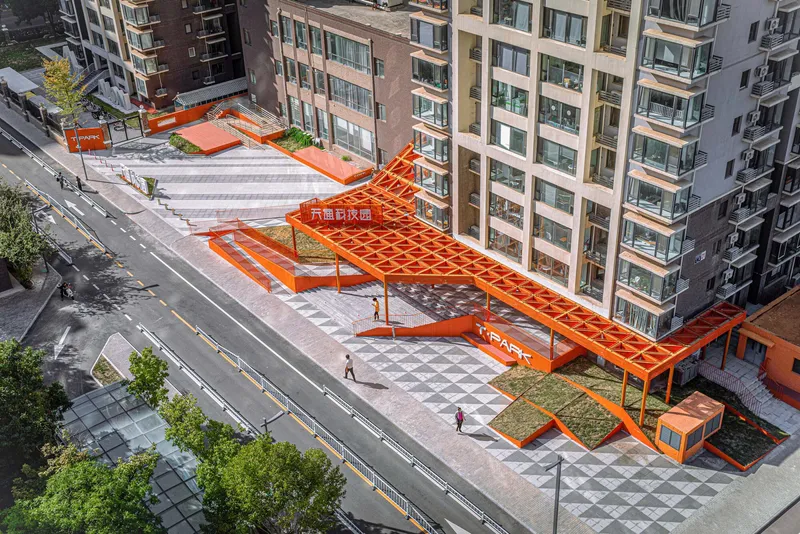 Aerial view of angled orange pedestrian canopy spanning patterned paving between residential buildings
