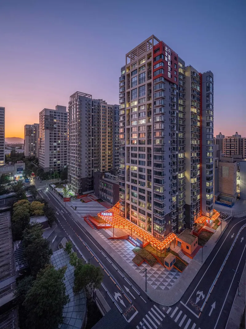 Elevated corner view of residential tower with orange canopy at base at dusk