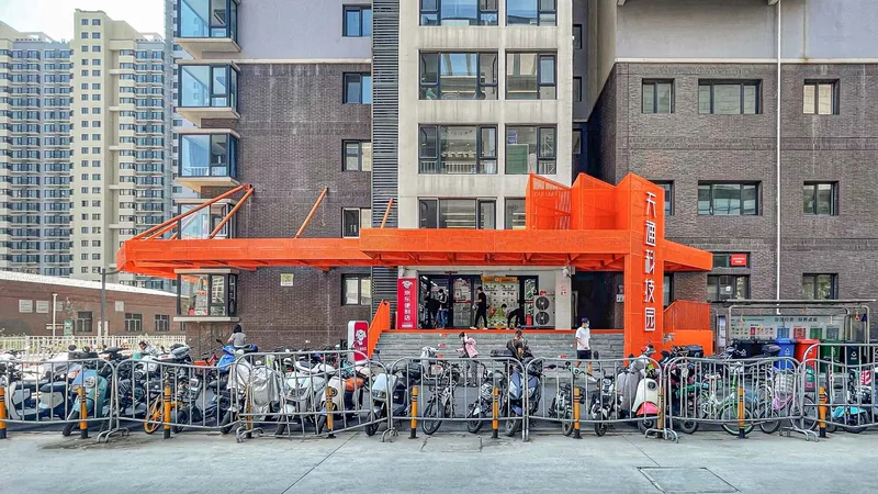 Orange steel pavilion elevated above a bicycle parking area in a residential courtyard