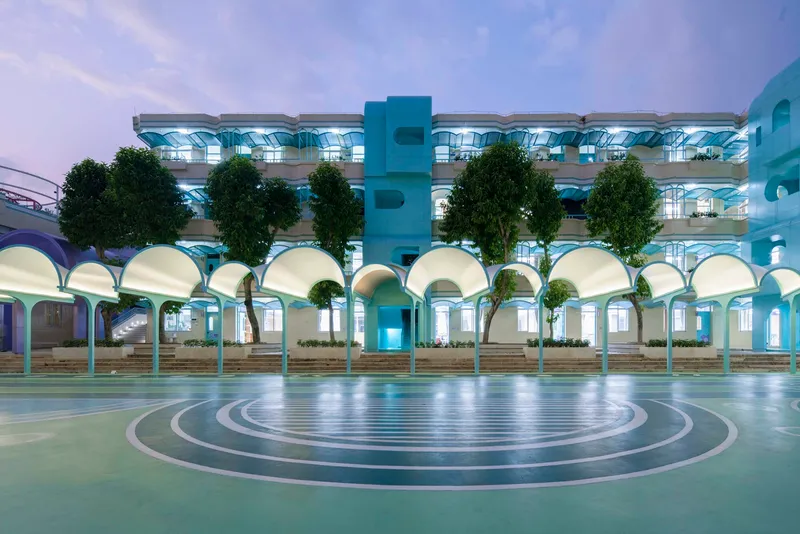 Courtyard with concentric circular paving and a multi-story arcade of vaulted arches under dusk light