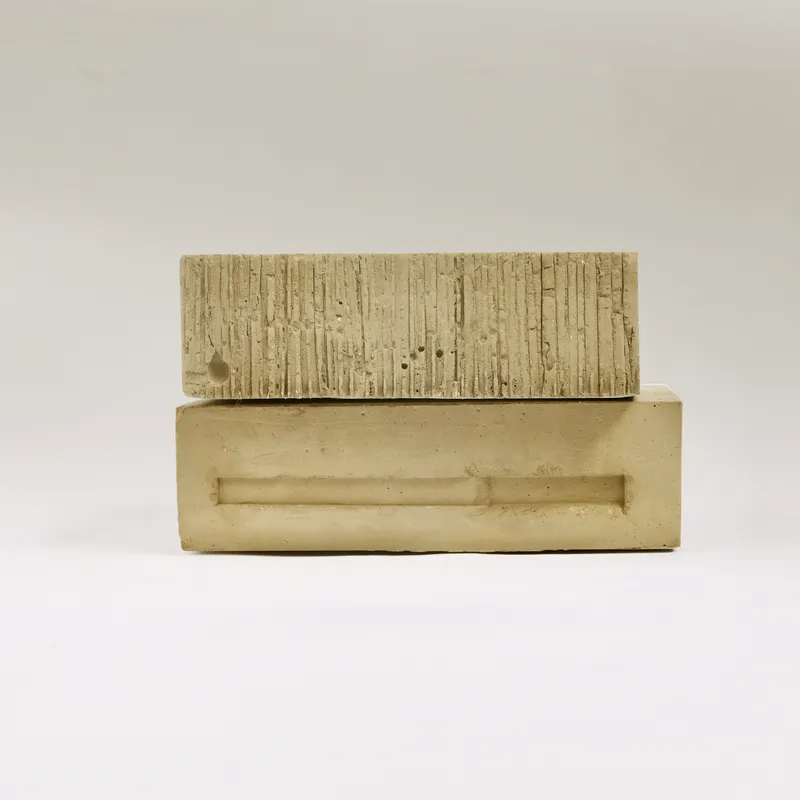 Side view of plaster model revealing board-formed facade and smooth base under neutral light