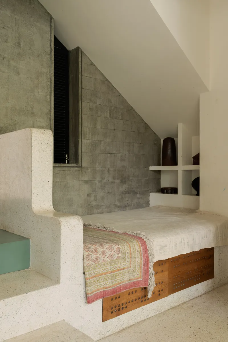 Built-in concrete daybed with timber storage compartment against a grey tile wall