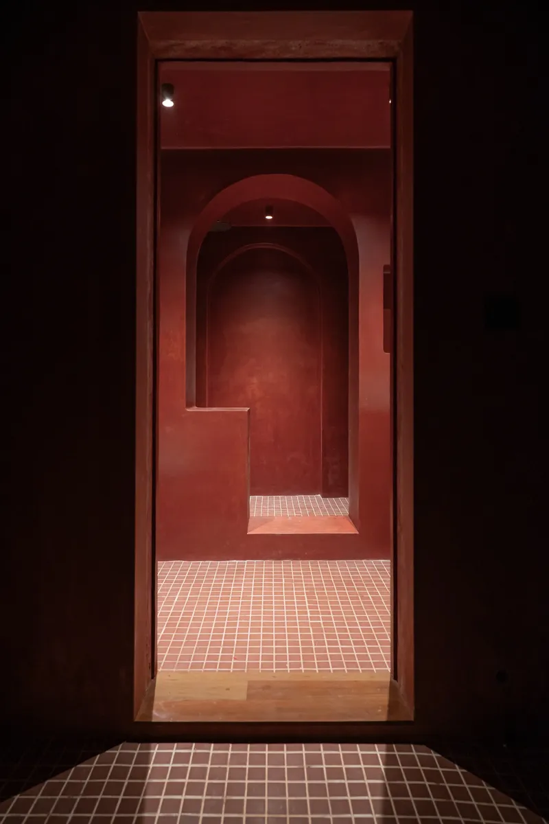 Sequence of arched doorways receding into darkness with tiled threshold and red plastered walls