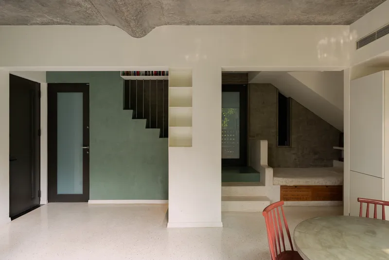 Interior view of floating staircase with integrated lighting treads ascending past a green textured wall