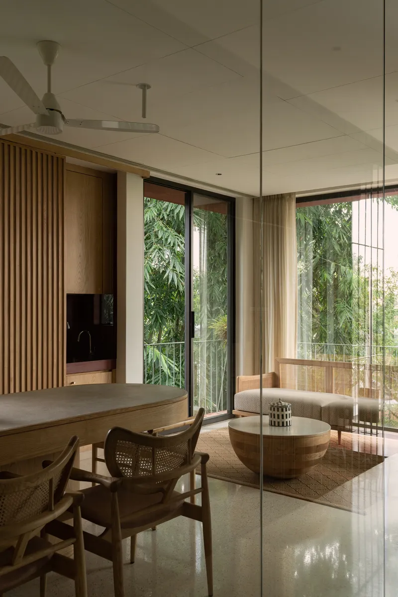 Open living and dining area with timber slat screen and glass doors opening to bamboo plantings