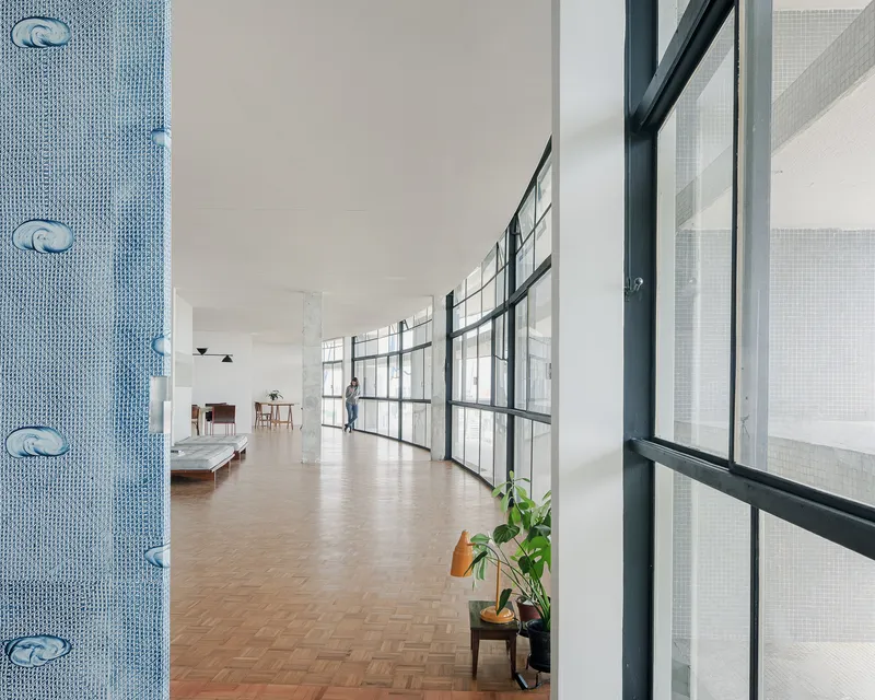 Long corridor with herringbone parquet flooring and grid-patterned glazing along one side