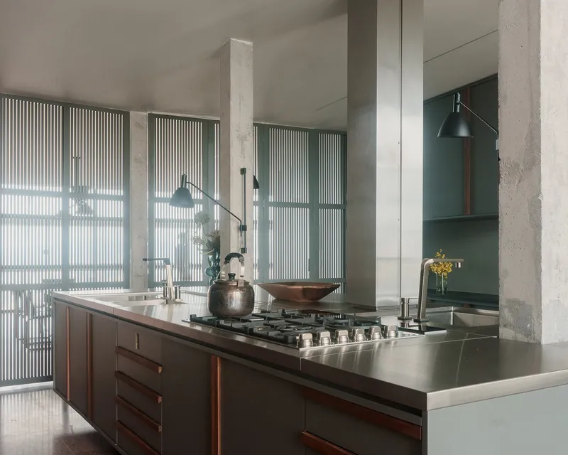 Kitchen island with stainless steel countertop and exposed concrete columns framing the space