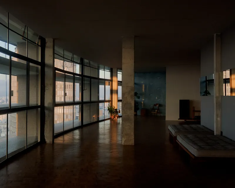 Corridor with steel-framed glazing along concrete columns during the golden hour