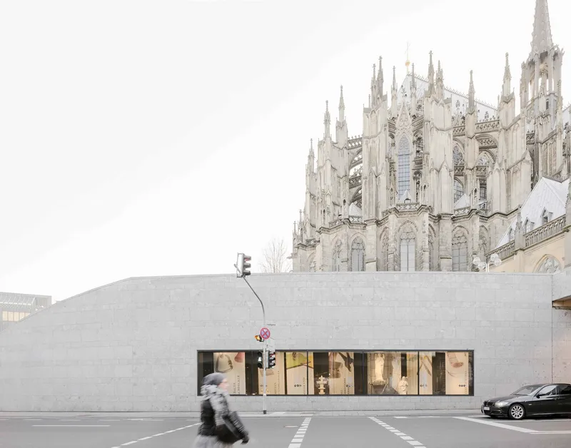 Concrete facade with horizontal storefront windows and a blurred pedestrian crossing the street
