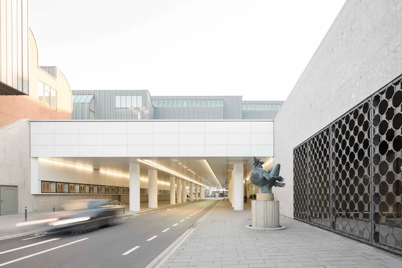 White bridge structure spanning a roadway with round columns and patterned metal screen wall in daylight