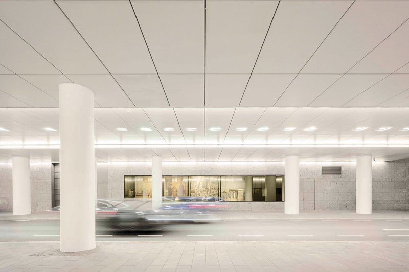 Underground parking level with white columns and recessed lighting as a car passes in motion blur