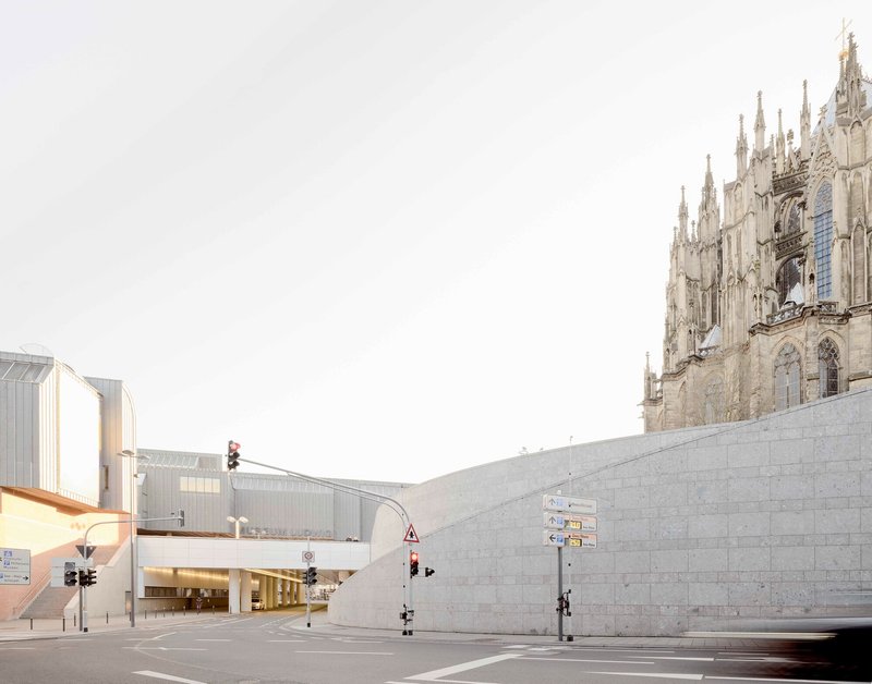Stone block retaining wall meeting an intersection beneath the spires of a gothic cathedral