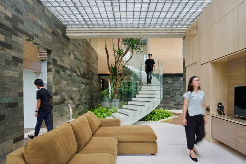 Living room with gridded skylight above stone accent wall and floating staircase flanked by planted beds